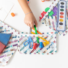 Load image into Gallery viewer, A child grabs art supplies from a Bumkins Clear Travel Bag 3 Pack: Mickey &amp; Friends Varsity on a white table.
