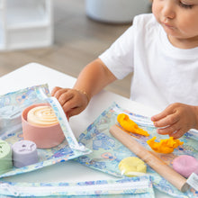 Load image into Gallery viewer, A child happily molds clay with a rolling pin on a Bumkins Clear Travel Bag 3 Pack: Aloha Stitch at a white table.
