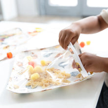 Load image into Gallery viewer, A child plays with pasta and pom-poms for sensory fun using Bumkins Clear Travel Bag 3-Pack: Winnie and Friends at a white table.
