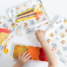 Load image into Gallery viewer, A child plays with magnetic tiles near Bumkins Clear Travel Bag 3-Pack: Winnie and Friends filled with pom-poms and markers on a table.
