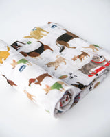 The Cotton Swaddle, Woof by Little Unicorn features colorful dogs—perfect as a baby swaddle blanket on any white surface.