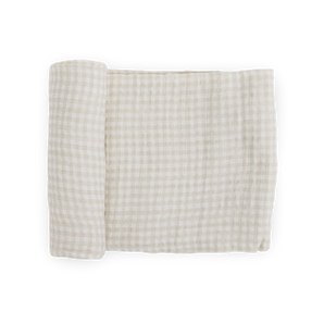 Little Unicorn Cotton Swaddle in Tan Gingham, partially rolled, shown on a white background.