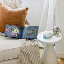 Load image into Gallery viewer, A childrens book, cozy chair, knitted blanket, brown cushion nearby with a plush rabbit and Tooth Fairy Flylight Box Set on a table.
