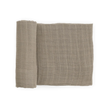 Little Unicorn Organic Cotton Muslin Swaddle Blanket in Driftwood, OEKO-TEX certified, pictured rolled and unrolled on white.