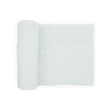 A Cotton Muslin Swaddle Blanket in Pale Pinstripe by Little Unicorn is partially unrolled on a white background.