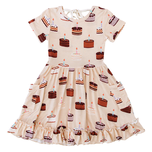 The Blake Birdie Dress by Birdie Bean features birthday cakes, candles, and a ruffled hem—perfect for any special moment.