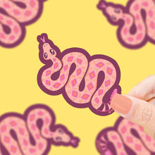 Load image into Gallery viewer, A hand with painted nails holds Turtle Soups Vinyl Sticker, Slithering Rattlesnake on a yellow background.
