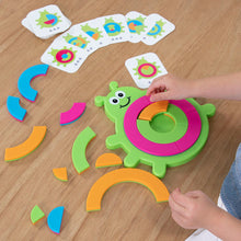 Load image into Gallery viewer, A childs hands tackle the Bugzzle Game by Fat Brain Toy Co, with vibrant puzzle and matching cards spread on the table.
