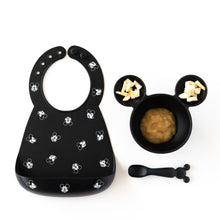 Load image into Gallery viewer, Bumkins Silicone Bib: Mickey Mouse Faces, sits next to a bowl with applesauce &amp; banana chunks and a matching spoon on a white background.
